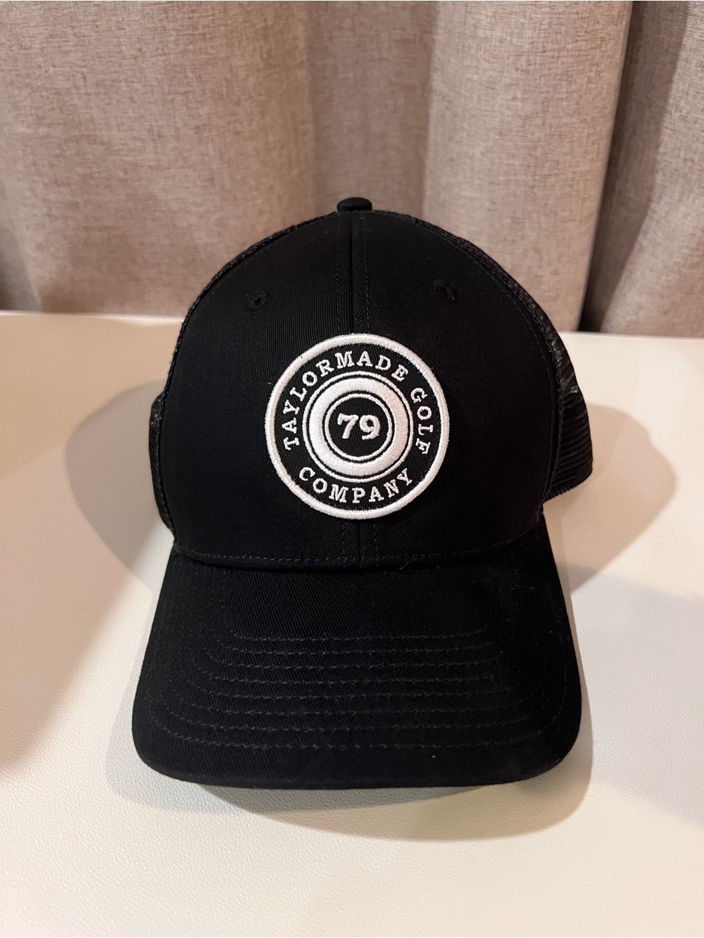 TaylorMade Golf Company black trucker cap w/ white circular logo featuring '79'